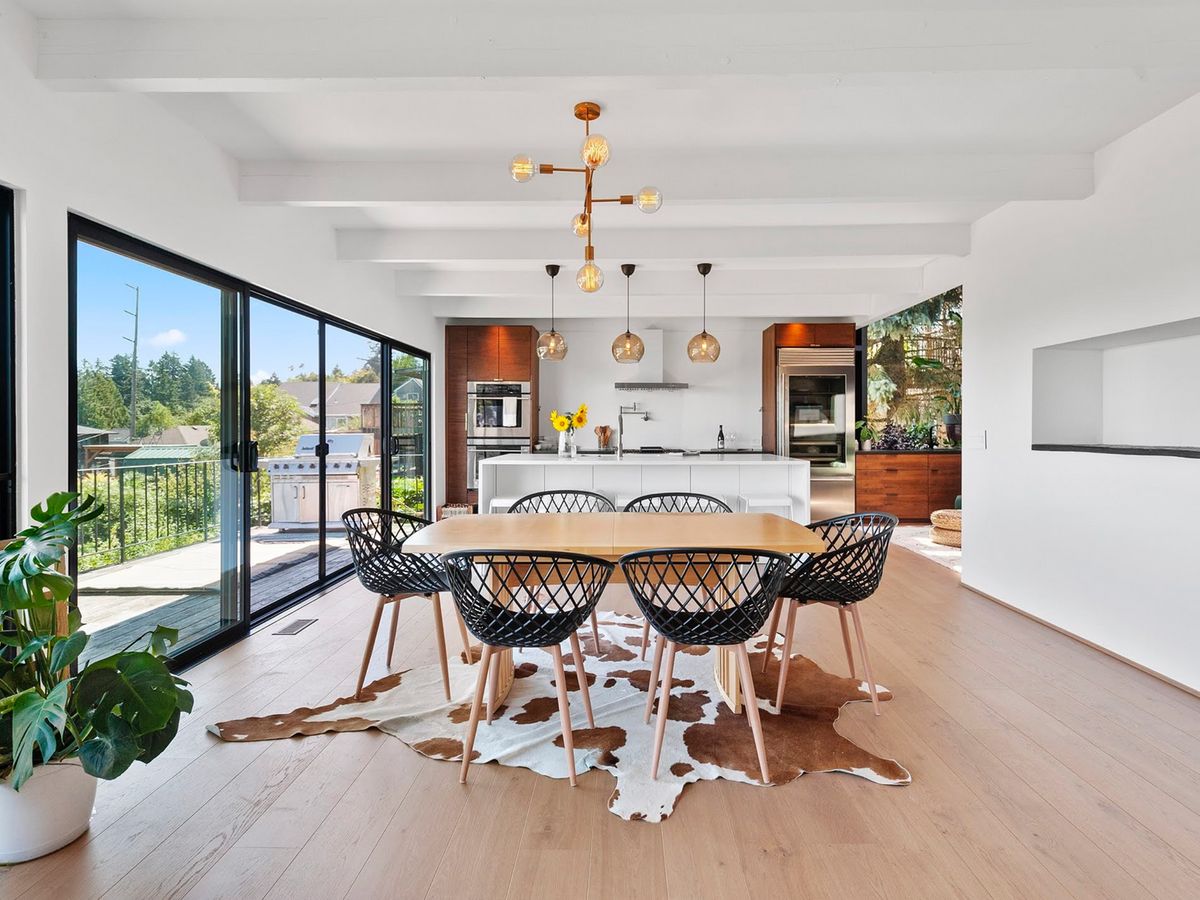 SW Waterfront renovation — dining and kitchen under exposed beams, opening to the deck